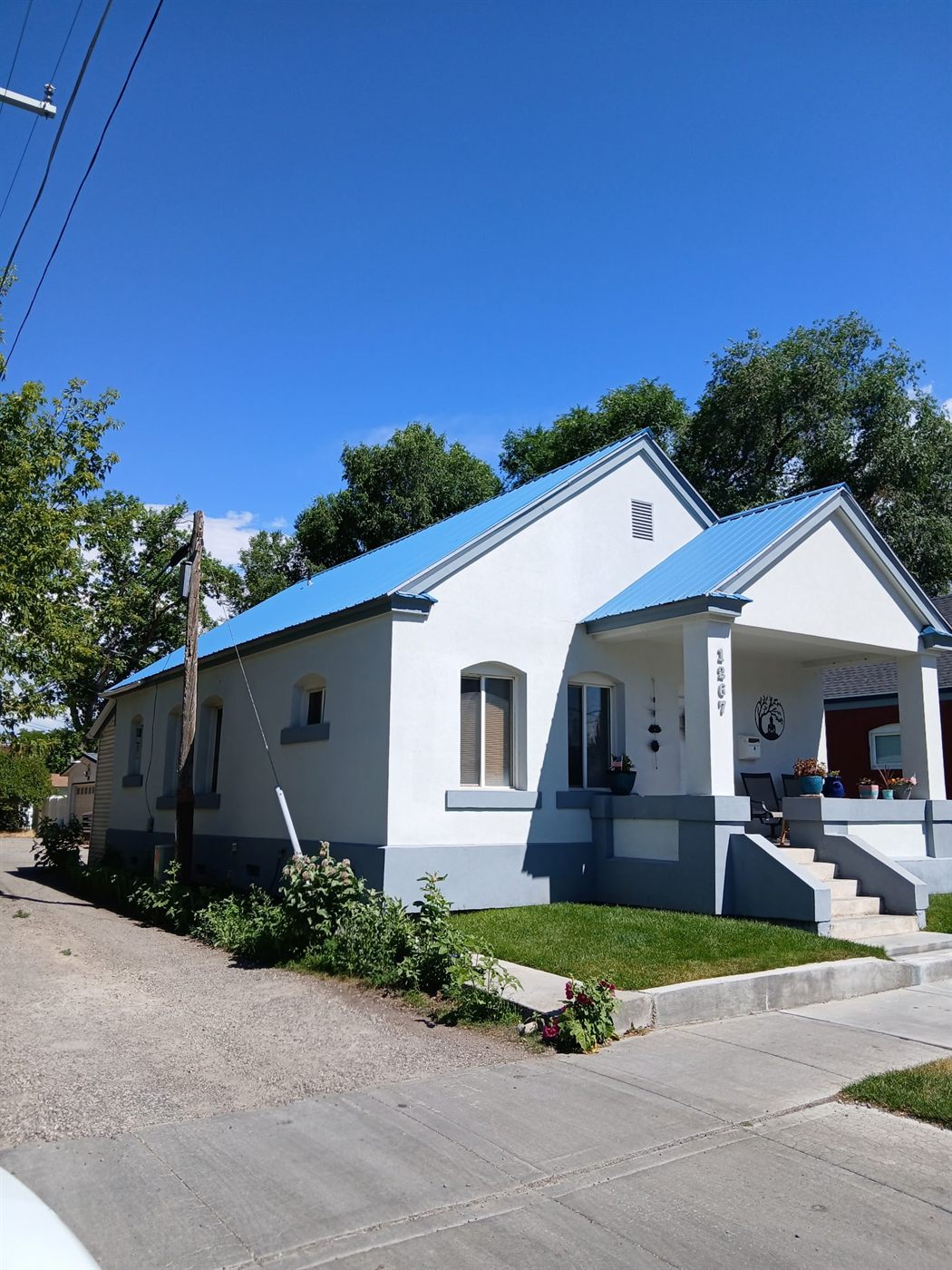 White stucco home with a new blue standing-seam metal roof installed by Secure Roofing and Siding in Southeastern Idaho